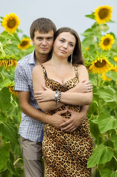 Junges Mädchen und ein junger Mann im Sonnenblumenfeld — Stockfoto