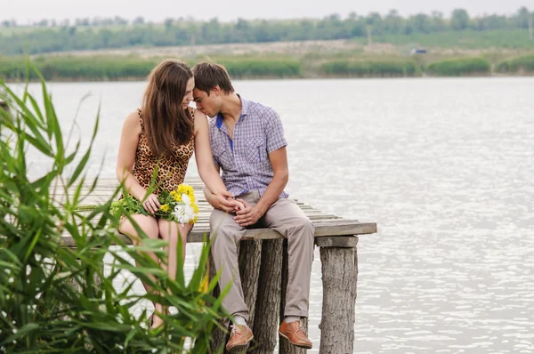 Молодая девушка и молодой человек на пристани у реки — стоковое фото