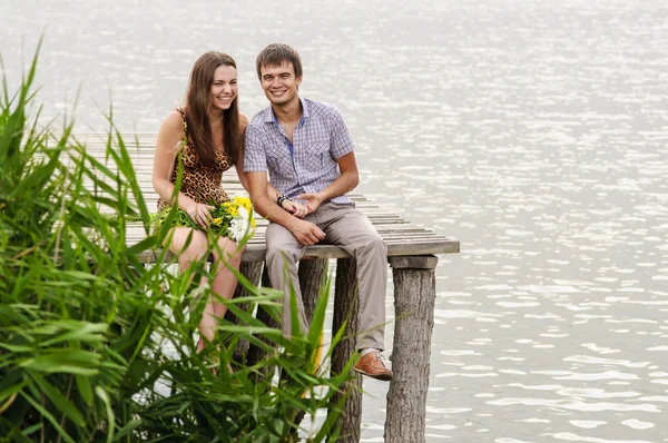 Giovane ragazza e il giovane sul molo vicino al fiume — Foto Stock