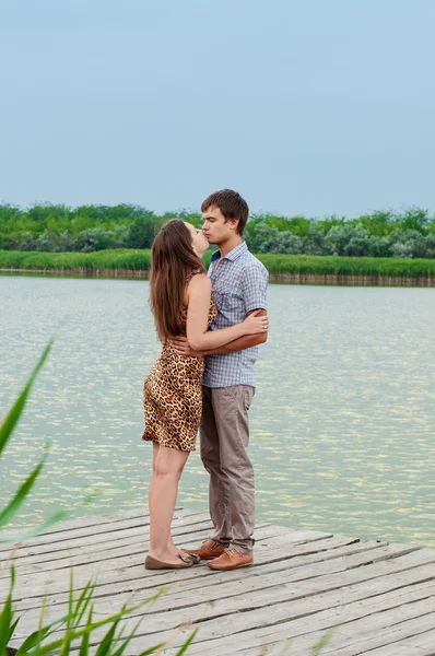 Young girl and the young man on the dock by the river — Stock Photo, Image