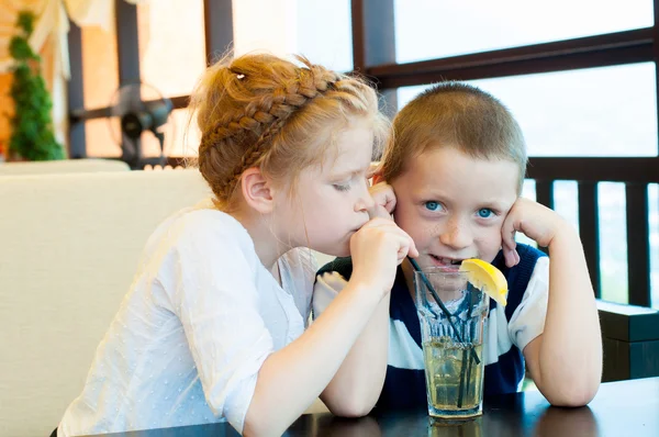 Boy and girl drinking a drink with ice through a straw — Stock Photo, Image