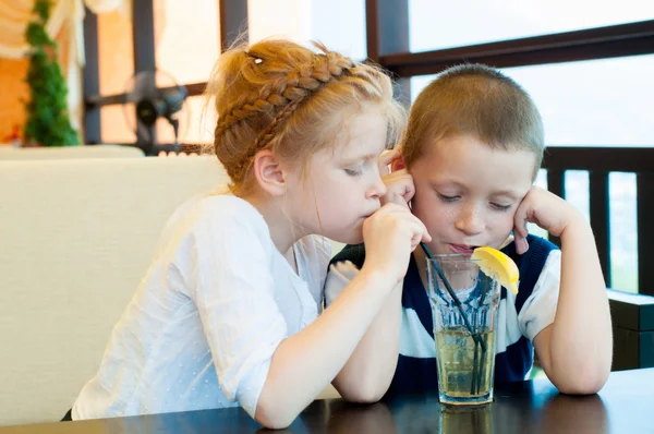 Boy and girl drinking a drink with ice through a straw — Stock Photo, Image