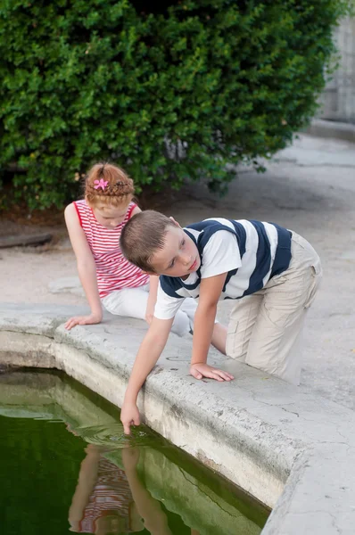 Menina e menino brincando na fonte — Fotografia de Stock