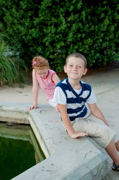 Chica y niño jugando junto a la fuente —  Fotos de Stock