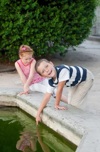 Ragazza e ragazzo giocando vicino alla fontana — Foto Stock