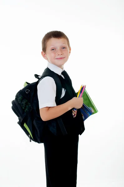 Niño pequeño con una mochila escolar y libros sobre fondo blanco — Foto de Stock