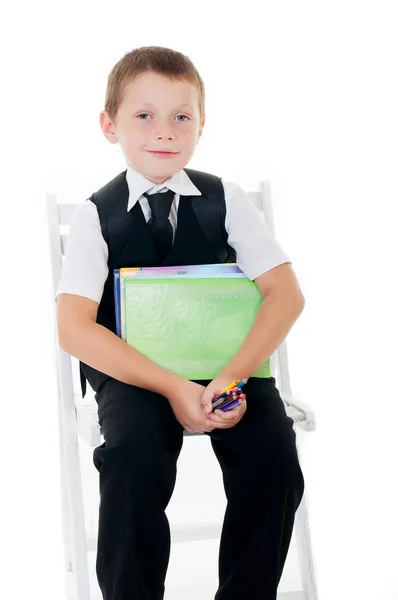 Kleine jongen in de stoel met potloden en boeken — Stockfoto