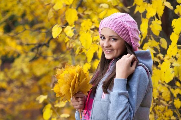 Jovem em um parque no outono com folhas amarelas — Fotografia de Stock