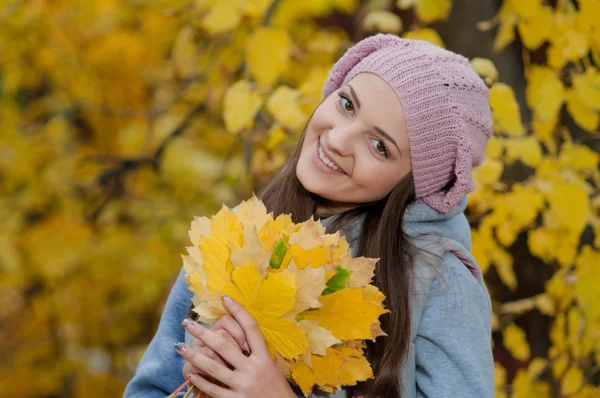 Молодая девушка в парке осенью с желтыми листьями — стоковое фото