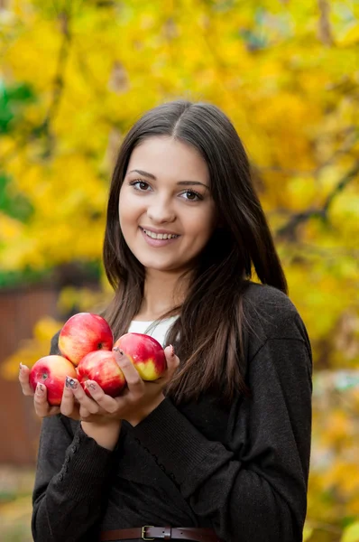 Mladá dívka v podzimním parku s jablky — Stock fotografie