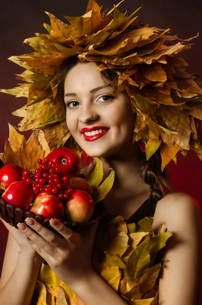 La jeune belle fille dans une couronne de feuilles jaunes avec un panier de fruits — Photo