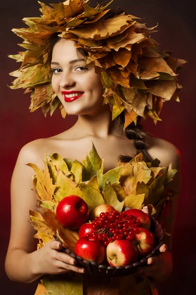 La jeune belle fille dans une couronne de feuilles jaunes avec un panier de fruits — Photo