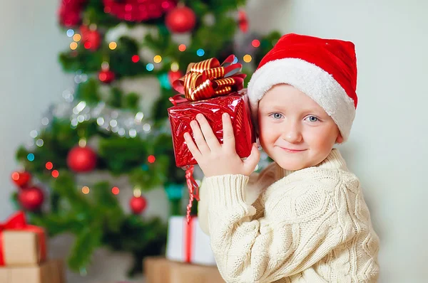 Liten pojke med gåvor nära en julgran — Stockfoto