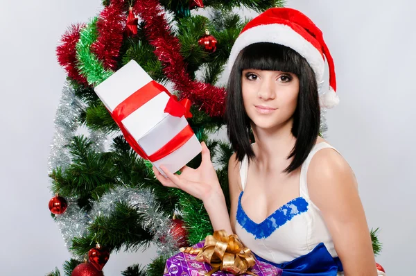 Όμορφη κοπέλα στη santa καπέλο κοντά ένα χριστουγεννιάτικο δέντρο — Φωτογραφία Αρχείου