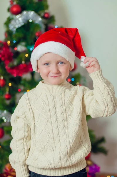 Liten pojke i santa hatt nära julgran — Stockfoto