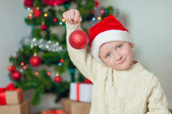 Liten pojke i santa hatt nära julgran — Stockfoto