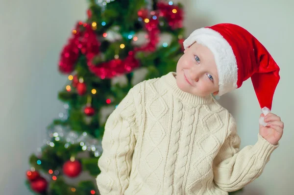 Little boy in santa hat near Christmas tree — Stock Photo, Image