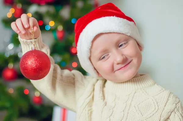 Little boy in santa hat near Christmas tree — Stock Photo, Image