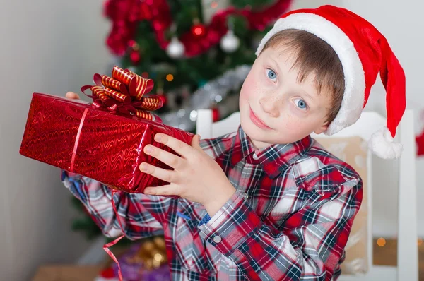 Menino em Papai Noel perto da árvore de Natal — Fotografia de Stock