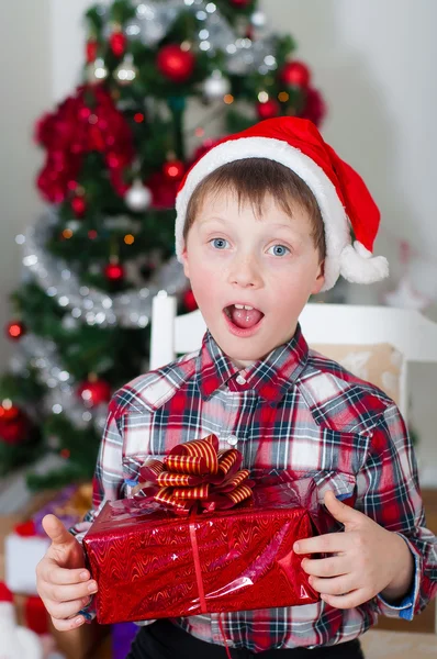 Menino em Papai Noel perto da árvore de Natal — Fotografia de Stock