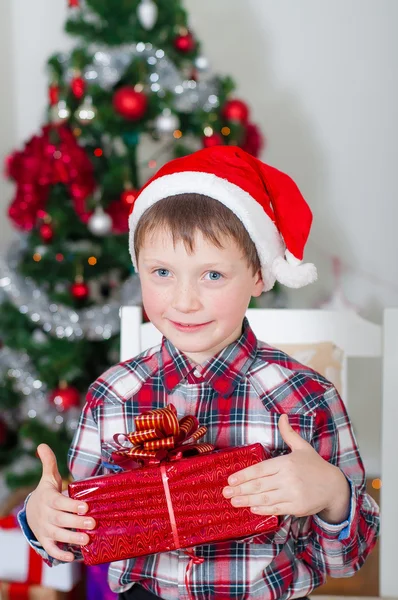 Liten pojke i santa hatt nära julgran — Stockfoto