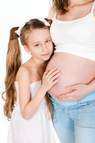 Little girl hugging her mother's pregnant belly — Stock Photo, Image