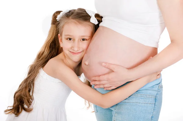 Meisje van haar moeder zwangere buik knuffelen — Stockfoto