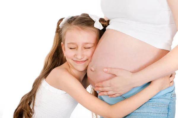 Küçük kız annesinin hamile karnına sarılma — Stok fotoğraf