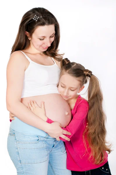 Liten flicka kramar hennes mor gravid mage — Stockfoto
