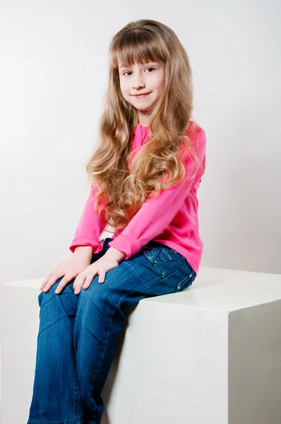 Menina com cabelos longos encaracolados em uma blusa rosa — Fotografia de Stock