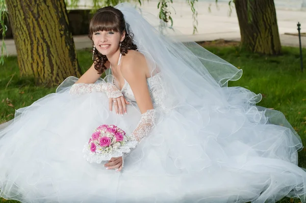 Beautiful bride in wedding dress with a bouquet of flowers on nature — Stock Photo, Image