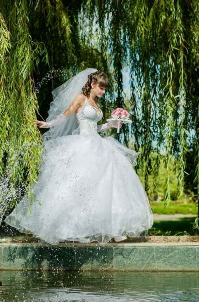 Красивая невеста в свадебном платье с букетом цветов на природе — стоковое фото