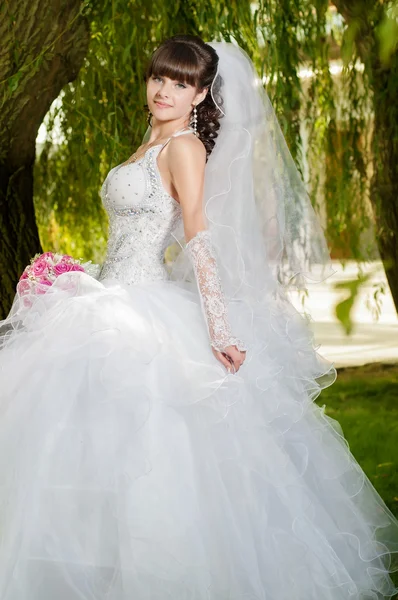 Красивая невеста в свадебном платье с букетом цветов на природе — стоковое фото
