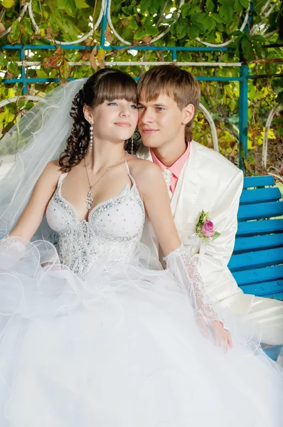 年轻、 漂亮的新娘和新郎坐在板凳上 — 图库照片