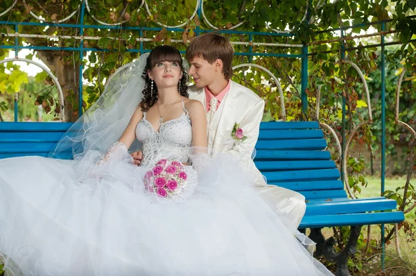 Young and beautiful bride and groom on the bench — Stock Photo, Image