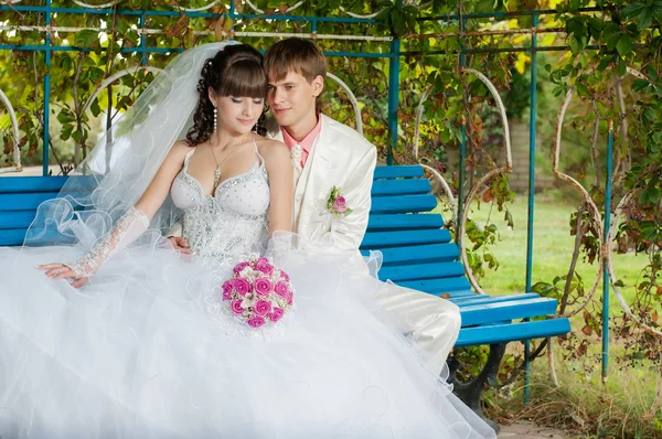 Young and beautiful bride and groom on the bench — Stock Photo, Image