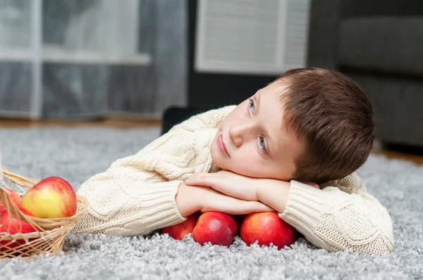与苹果的男孩躺在家里的地毯上 — 图库照片