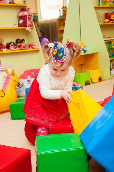 Klein meisje spelen met speelgoed in de speelkamer — Stockfoto