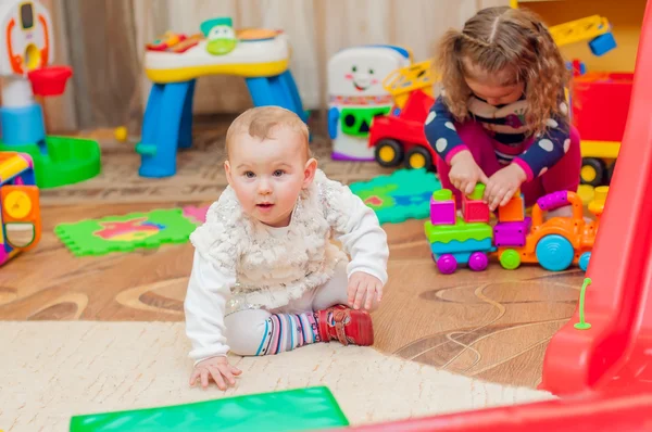 Klein meisje spelen met speelgoed in de speelkamer — Stockfoto
