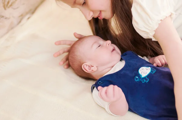 Oudere zus knuffelen baby liggend — Stockfoto