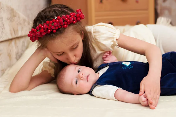 Ältere Schwester umarmt Baby liegend — Stockfoto