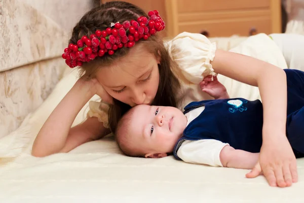 Oudere zus knuffelen baby liggend — Stockfoto