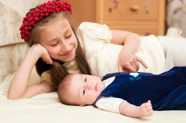 Ältere Schwester umarmt Baby liegend — Stockfoto