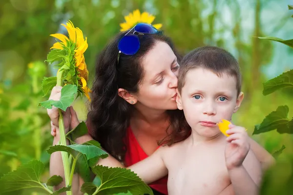 Mother and son in a field of sunflowers in summer — Stock Photo, Image