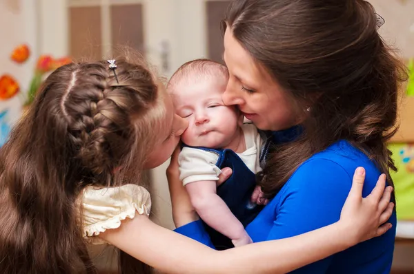 Mamma kramar baby och äldre dotter — Stockfoto