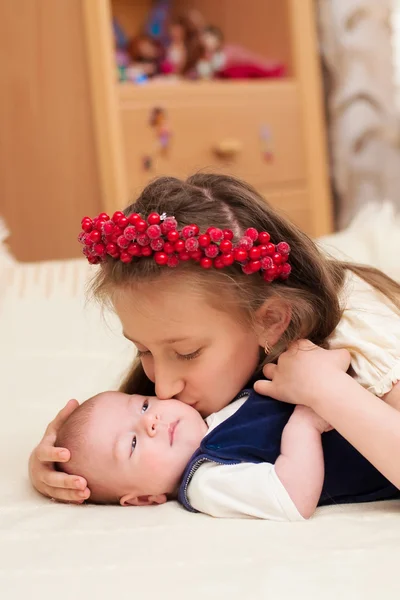 Ältere Schwester umarmt Baby liegend — Stockfoto