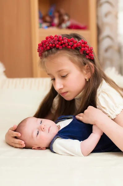 Oudere zus knuffelen baby liggend — Stockfoto