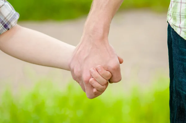 Handen van vader en een kind in de natuur — Stockfoto