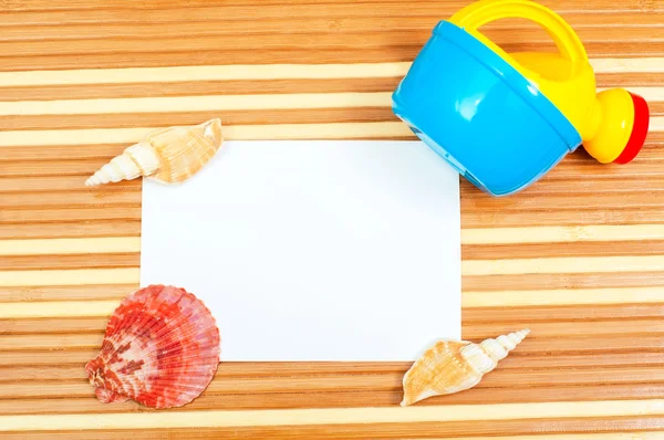 Tarjeta de papel y conchas marinas pala de juguete en madera — Foto de Stock