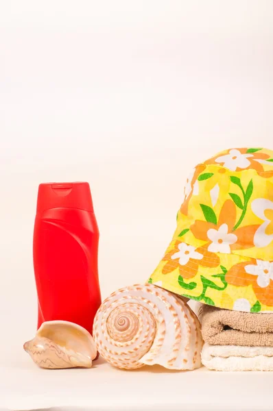 Бутылка шампуня и полотенца ракушки летняя шляпа — стоковое фото
